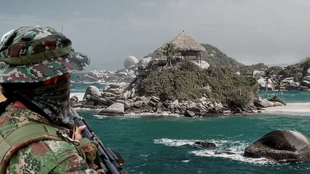 Hombre con uniforme de camuflaje y un arma frente a una costa con vegetación y construcciones turísticas.